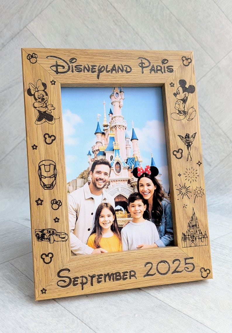 May include: Wooden photo frame with the text "Disneyland Paris" and "September 2025" engraved. The frame features Disney character illustrations and holds a family photo in front of a castle.