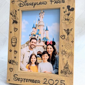 May include: Wooden photo frame with the text "Disneyland Paris" and "September 2025". The frame features etched Disney character designs and a family photo in front of a castle.