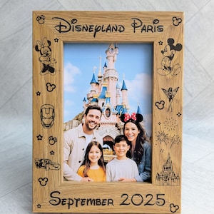May include: Wooden photo frame with the words "Disneyland Paris" and "September 2025" engraved. The frame features etched Disney character designs and holds a family photo in front of a castle.
