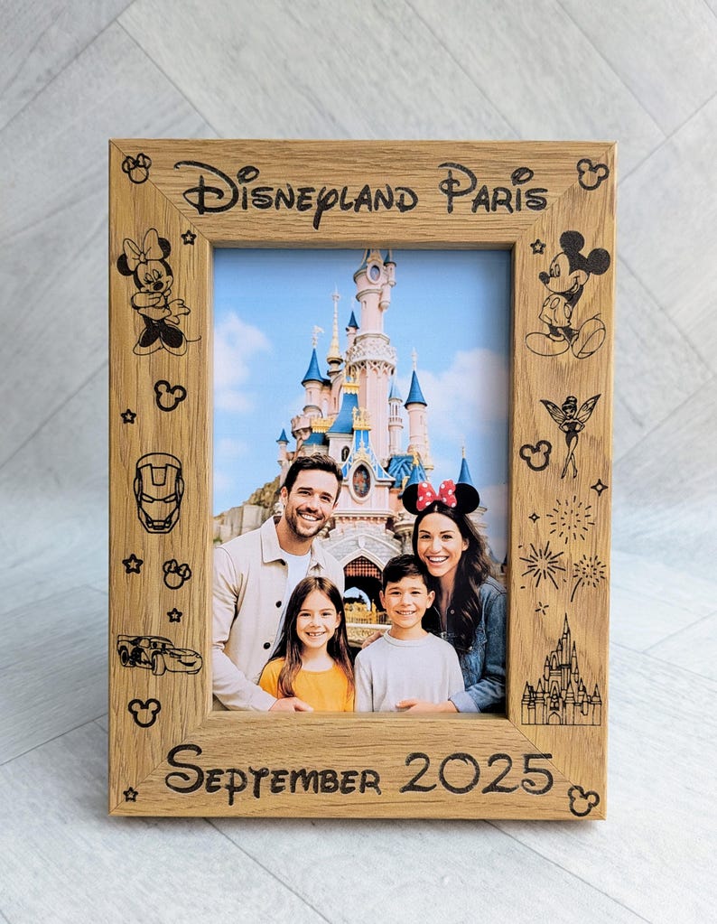 May include: Wooden photo frame with the words "Disneyland Paris" and "September 2025" engraved. The frame features etched Disney character designs and holds a family photo in front of a castle.