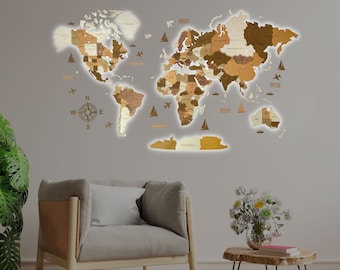 May include: A wooden world map with a compass and airplanes on a light gray wall. The map is surrounded by a white glow. A gray armchair and a wooden side table with a book on top are in the foreground.