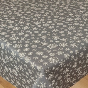 May include: A grey tablecloth with a white snowflake pattern. The tablecloth is made from a durable, easy-to-clean material.