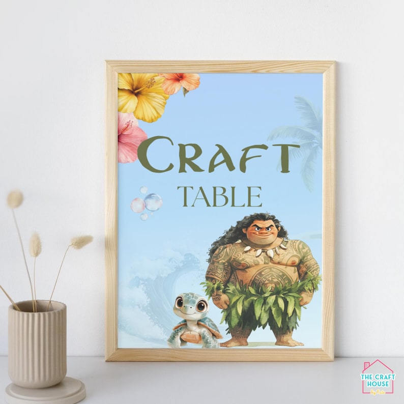 May include: A printable sign with a blue background and a tropical theme. The sign says "Craft Table" in green text. There are images of Moana and Pua from the Disney movie Moana.