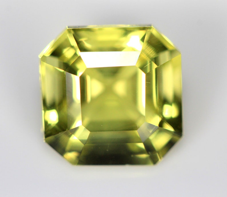 May include: A light green gemstone with a square emerald cut.