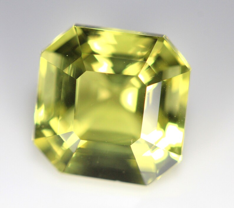 May include: A light green gemstone with a square emerald cut.