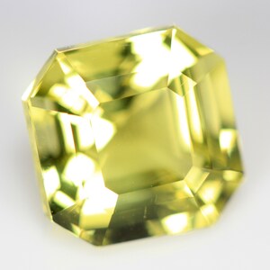 May include: A yellow gemstone with a square cut and a faceted finish.