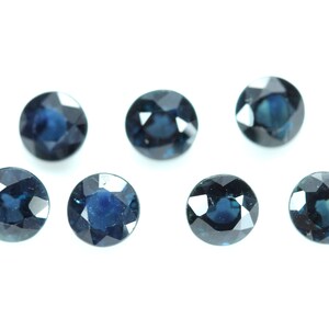 May include: Eight round, faceted, dark blue gemstones. The gemstones are arranged in two rows of four, with the top row slightly offset from the bottom row.
