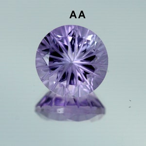 May include: A close-up of a purple amethyst gemstone with a star-shaped cut. The gemstone is faceted and has a high polish. The text "AA" is visible above the gemstone.