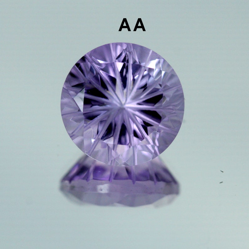 May include: A close-up of a purple amethyst gemstone with a star-shaped cut. The gemstone is faceted and has a high polish. The text "AA" is visible above the gemstone.