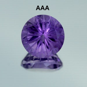 May include: A round, purple amethyst gemstone with a starburst pattern cut into the surface. The gemstone is labeled "AAA" indicating its quality.