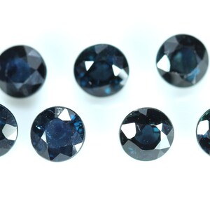 May include: Seven round, dark blue gemstones with a faceted cut.