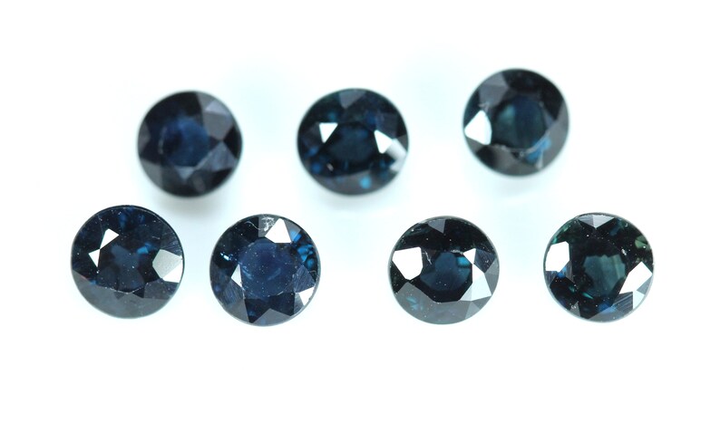 May include: Seven round, dark blue gemstones with a faceted cut.