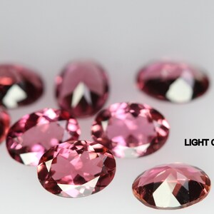 May include: A group of eight oval-shaped, light pink gemstones. The gemstones are faceted and have a high shine.  LIGHT COLOR