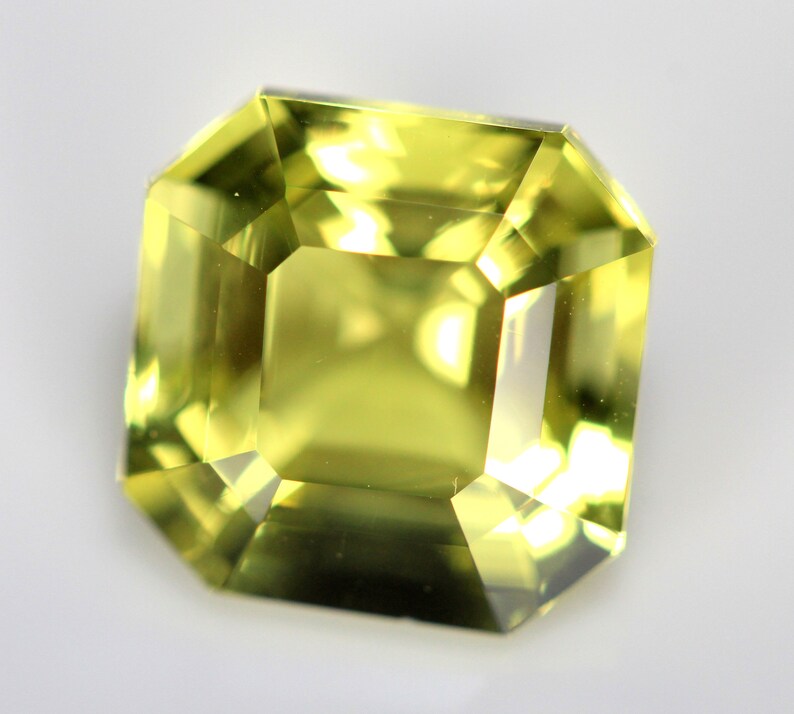 May include: A light green gemstone with a square emerald cut.