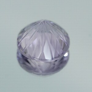 May include: A faceted, clear, purple gemstone with a pointed top.