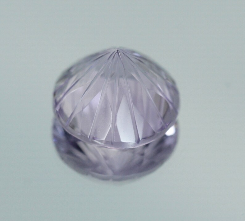 May include: A faceted, clear, purple gemstone with a pointed top.