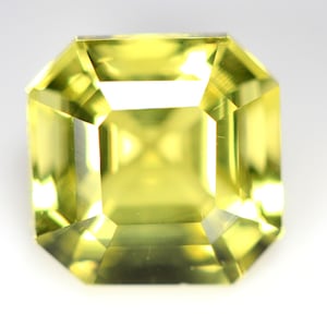 May include: A bright yellow gemstone cut into an emerald shape.