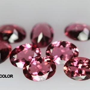 May include: A group of seven oval-shaped, light pink gemstones. The gemstones are faceted and have a shiny, polished finish.