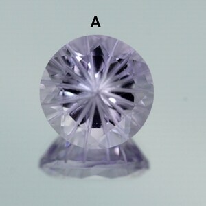 May include: A clear, faceted gemstone with a starburst pattern in the center. The gemstone is a light purple color and has a reflective surface.