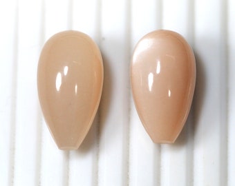 May include: Two teardrop-shaped, light peach-coloured gemstone beads.