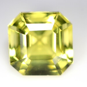 May include: A light yellow gemstone with a square emerald cut. The gemstone is faceted and has a high degree of clarity.