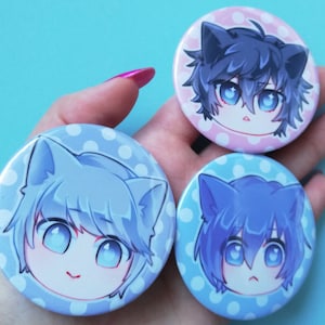 May include: Three round pinback buttons with white polka dot backgrounds. Each button features a cartoon character with blue, purple, or grey hair and cat ears. The characters have large blue eyes and are smiling or frowning.