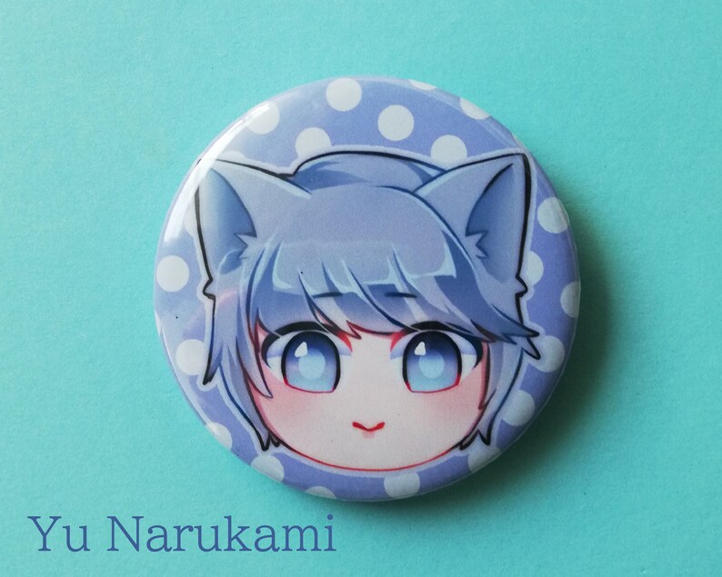May include: A blue and white polka dot button featuring a cartoon character with blue hair, blue eyes, and cat ears. The character's name is "Yu Narukami".