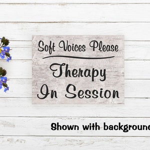May include: A white wooden sign with black text that reads "Soft Voices Please Therapy In Session". The sign is shown against a white wood background.