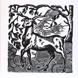 May include: A black and white linocut print on paper featuring a standing deer with large antlers. The deer's body is decorated with small star shapes. The background shows stylized trees, swirling ground patterns, and clouds in a bold graphic style.