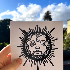 Pode incluir: Impress&atilde;o em preto e branco de um sol estilizado com um rosto humano. A impress&atilde;o &eacute; assinada "Sofia Krashelev 2023".