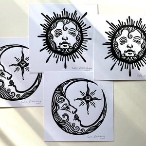 Pode incluir: Quatro impress&otilde;es em lin&oacute;leo em preto e branco de uma lua crescente e um sol com rosto. Cada impress&atilde;o tem o nome do artista e o ano de 2021.