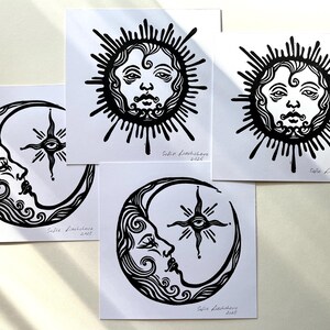 Pode incluir: Quatro impress&otilde;es em lin&oacute;leo em preto e branco de uma lua crescente e um sol com rosto. Cada impress&atilde;o tem o nome do artista e o ano de 2021.