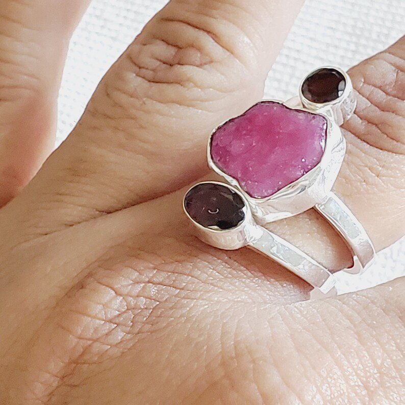 Peut inclure: Une bague en argent avec trois pierres pr&eacute;cieuses. La plus grande pierre est rose et de forme irr&eacute;guli&egrave;re. Les deux autres pierres sont rondes et brun fonc&eacute;.