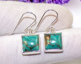 May include: A pair of silver dangle earrings with square turquoise stones. The stones have a green and gold color.