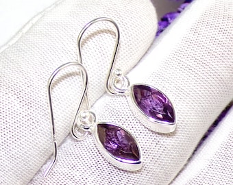 May include: A pair of silver dangle earrings featuring purple amethyst gemstones. The earrings have a simple design and are ideal for everyday wear.
