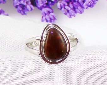 May include: A silver ring with a teardrop-shaped red gemstone set in a silver bezel.