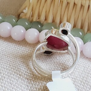 Peut inclure: Une bague en argent avec une grande pierre pr&eacute;cieuse rose en forme de c&oelig;ur. La bague a une petite pierre pr&eacute;cieuse noire sur le c&ocirc;t&eacute;.