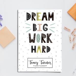 May include: A white planner with black polka dots and the text "DREAM BIG WORK HARD" in colorful, stylized lettering. The planner is personalized with the name "Tracey Turner" and the year "2023".