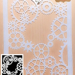 May include: A white mylar stencil with a laser-cut steampunk gear design. The stencil showcases various sizes of interlocking gears, with the words "Durable Laser Cut Mylar" on a brown label. A smaller, black and white version of the design is in the lower left corner.