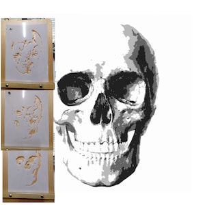 May include: A black and white skull stencil on a wooden easel. The stencil is in three stages of completion, showing the progression of the artwork.