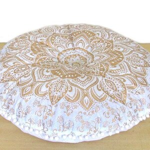 May include: Round floor cushion with a gold and white mandala design. The cushion has a buttoned center and is trimmed with white pom-poms. The cushion is approximately 30 inches in diameter.