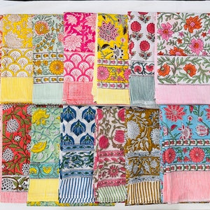 May include: A collection of 12 colourful cotton napkins with floral and geometric patterns. The napkins are arranged in two rows of six, with each napkin having a different design. The napkins are all approximately 45 cm by 45 cm.