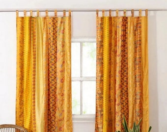 May include: A pair of yellow and orange patterned curtains with a patchwork design. The curtains are hung on a white rod and are made of a soft, flowing fabric.