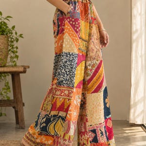 Op de afbeelding: Wijdvallende broek met een levendig patchworkontwerp met diverse bloemen-, geometrische en paisley-patronen in tinten oranje, geel, blauw en rood. De broek heeft een elastische tailleband met een trekkoord en zijzakken.