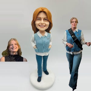 May include: A custom bobblehead figurine of a woman with red hair, wearing a light blue vest, white shirt, and blue pants. The figurine is standing on a white base. There is a photo of the woman on the left and a photo of the woman wearing the same outfit on the right.