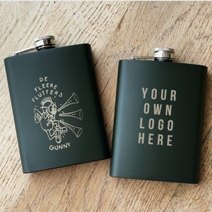 May include: Two green metal hip flasks. One flask features a graphic of a cartoon character playing a musical instrument with the text "De Fleere Fluiters Gunny". The other flask has the text "Your Own Logo Here".