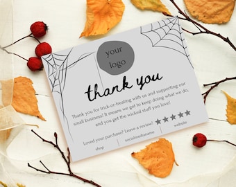 May include: A rectangular thank you card with a light gray background, black spider web illustrations in the corners, and a dark gray circle for a logo. The text reads thank you, followed by a message about trick-or-treating and small business support, plus five stars, website, shop, and socialmedianame placeholders.