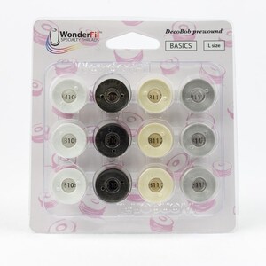 Puede incluir: Un paquete de 12 bobinas pre-enrolladas DecoBob para máquinas de coser. Las bobinas están en una caja de plástico transparente con fondo blanco. Las bobinas están etiquetadas con los números 310, 311 y 11. El paquete está etiquetado como "DecoBob pre-enrolladas" y "BASICS".
