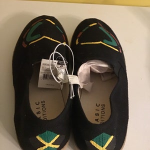 May include: A pair of black canvas slip-on shoes with a yellow, green, and black Jamaican flag design on the toe. The shoes have the text "ASIC  EDITIONS" on the side.