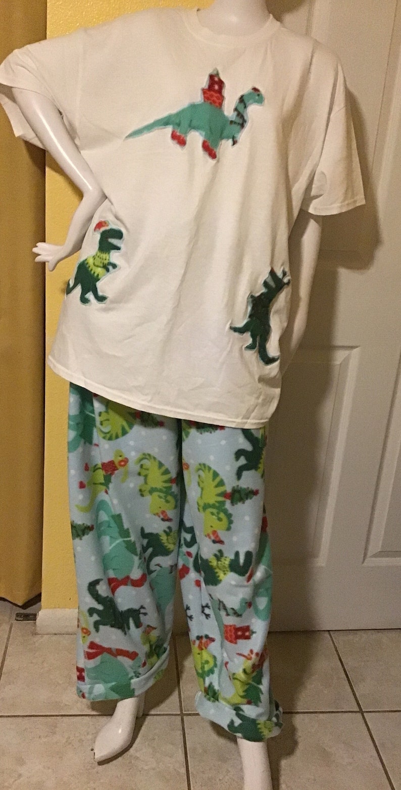 Puede incluir: Camiseta blanca con aplicaciones de dinosaurio verde y pantal&oacute;n de pijama a juego azul y verde con estampado de dinosaurio.